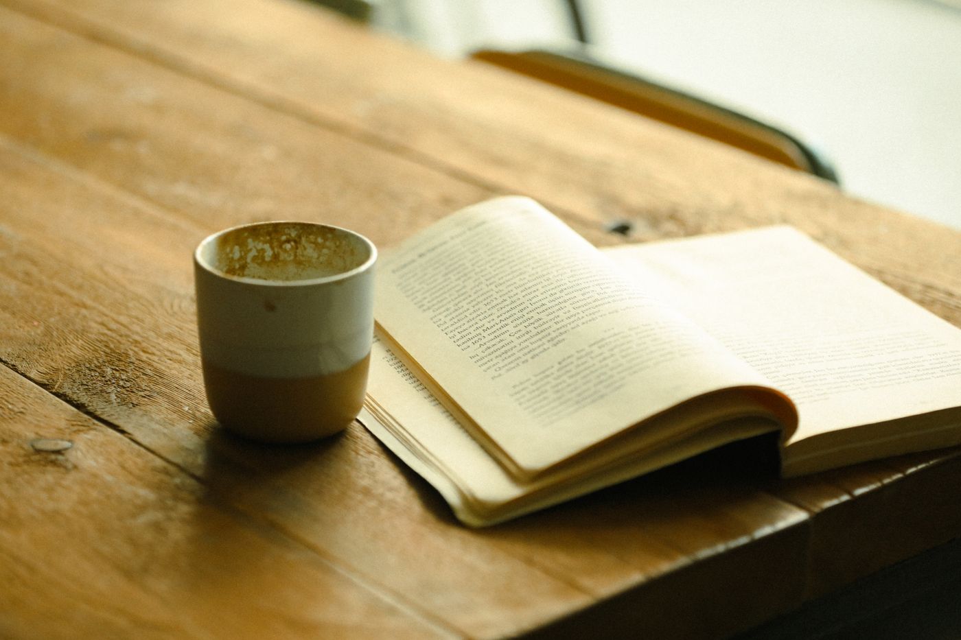 A warm wooden table with a mug and an open book in soft morning light